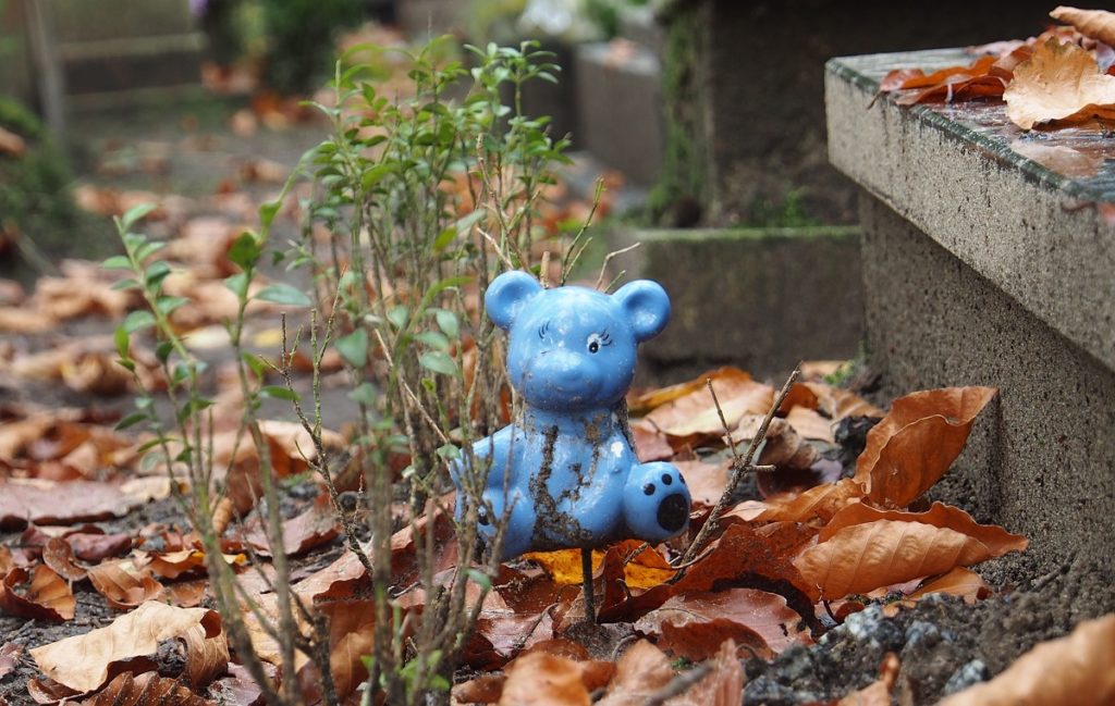Zabawka dziecięca - niebieski miś - przy grobie dziecięcym, ilustracja do artykułu o raporcie NIK