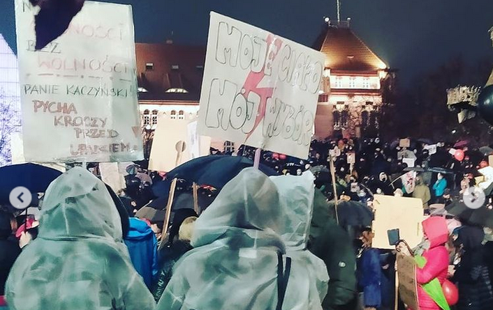 Strajk Kobiet, demonstracja, w deszczu stoją kobiety z transparentami "moje ciało, mój wybór"