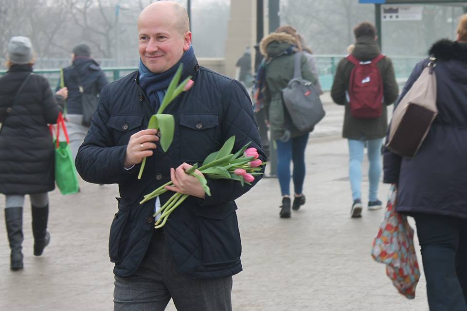 Bartłomiej Wróblewski na ulicy, w zimnie, rozdaje tulipany w Dzień Kobiet